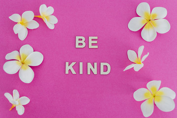 Be Kind message on pink background surrounded by flowers, concept of positive behaviours