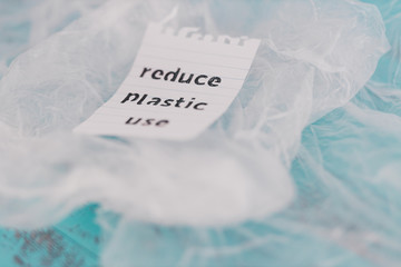 Reduce plastic use message on top of a bunch of plastic bags, sustainable living