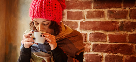 young woman in a pink hat enjoys drinking coffee