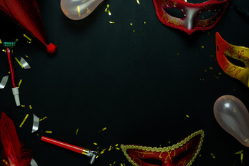 Table top view aerial image of beautiful colorful carnival festival background.Flat lay accessory object the several mask & decor confetti on modern black wooden at home office desk studio.copy space.