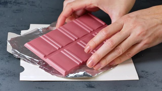 Breaking Ruby chocolate bar on pieces. New dimension of chocolate sweets.
