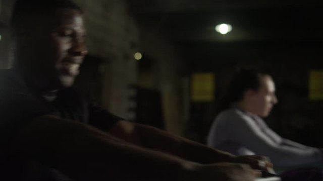 Slow motion of African American man and caucasian woman on rowing machines