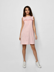 Young beautiful woman posing in new fashion long casual pastel pink color dress happy smiling walking on white