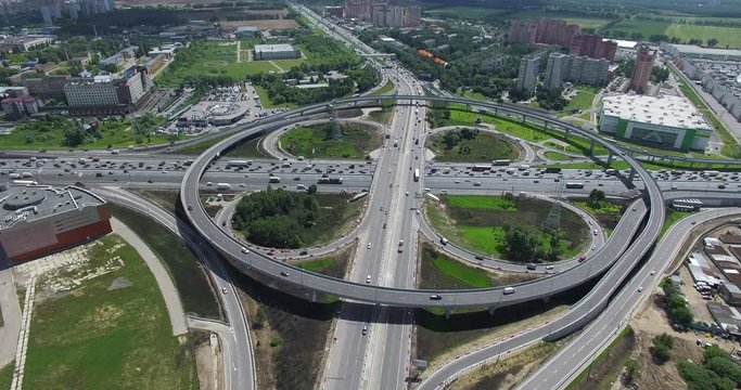 Aerial shot of car traffic on large cloverleaf interchange with circular overpass. Transport infrastructure in big city