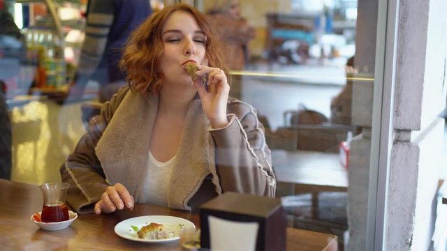 Redhead girl in the cafe eat sweets