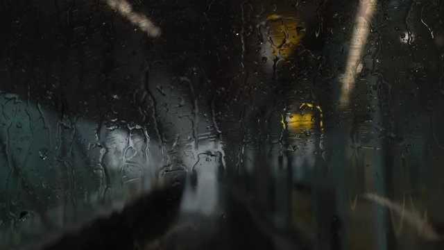 4K Defocused point of view of railway arriving to station in raining day seen through the train windshield during raindrops. Rain falling on railway window in rush hour working day.