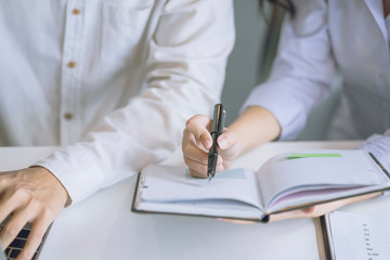 Close up of  business co-worker hand pointing at business document during discussion at meeting. businessman and businesswoman discussing information at the office.