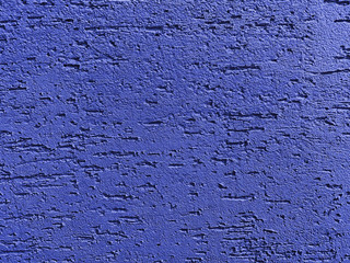 Structural putty stucco wall surface with cracks, painted into dark blue color. Colour trend of the...