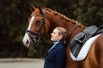 Foto op Canvas Reiterin steht auf einem Turnier an der Schulter ihres Pferdes © Talitha