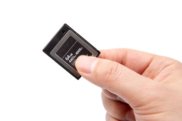 Man's hand holding XQD card on a white background.