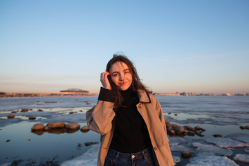 Portrait of a beautiful girl in raincoat, winter Gulf of Finland.