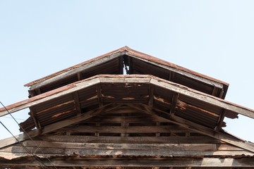 Fototapeta na wymiar Ruins of an abandoned wooden house, rusty galvanized sheet roof