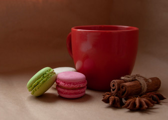 Red cup with macaroon and spices on craft paper background