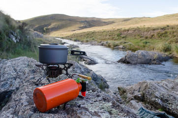 Hornillo multicombustible cocina campamento con río de fondo