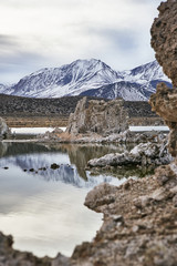 View of a Saline Soda Lake with Snow Capped Eastern Sierra Navada Mountains on a Cloudy Day in the Afternoon with Sunlight Shinning Through the Cloud 