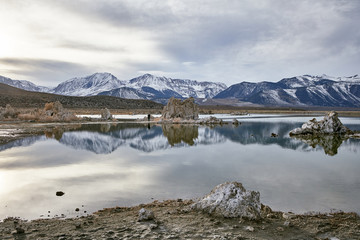 View of a Saline Soda Lake with Snow Capped Eastern Sierra Navada Mountains on a Cloudy Day in the Afternoon with Sunlight Shinning Through the Cloud 
