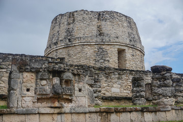 Fototapeta na wymiar Mayapan, Yucatan, Mexico: El Templo Redondo -- The Round Temple -- with ancient Mayan carvings in the foreground.
