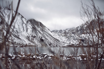 View of Lake on the Mountains in Winter Fog with Dramatic Snow Capped Mountains in the Background 