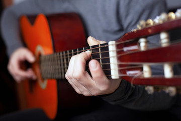man playing with acoustic orange guitar. the art of playing a stringed classical musical instrument.