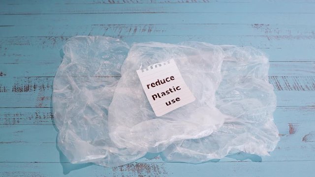 sustainable living Reduce plastic use message with wooden peg on top of plastic bags and in camera zooming