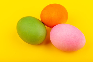 Colorful handmade Easter eggs. Top view of three eggs. Isolated on a yellow background. Preparing for Easter.