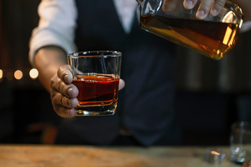 whiskey into the glass at the bar counter.