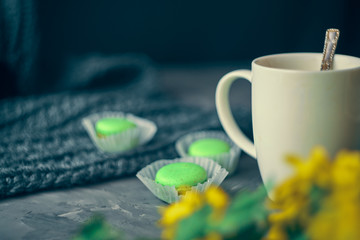Hot coffee with milk or cream and green macaroons on the loft table in a romantic setting with chrysanthemums nearby