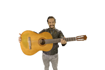 Obraz premium portrait of attractive latin man in rock star jacket, on white background, showing acoustic guitar to the camera