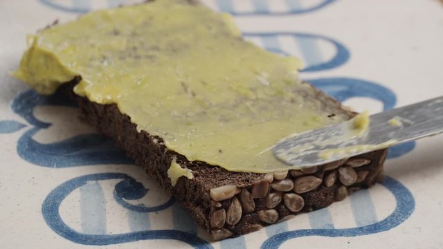 Close-up shot of making a healthy snack with rye dark bread and avocado spread