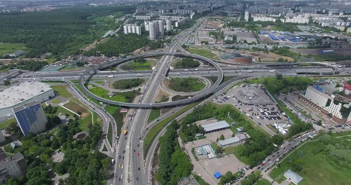 Aerial summer urban scene. Flying over huge cloverleaf intersection with circular overpass. Moscow traffic, Russia