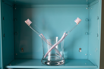 Two pink toothbrushes in glass on blue metal cabinet, About LGBT lifestyle, Bathroom concept