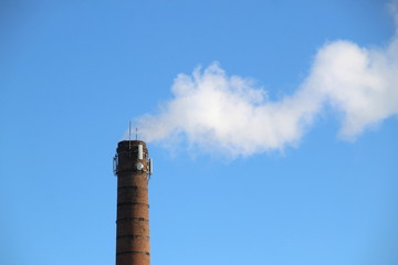 Smoke comes out of the chimney against a blue sky