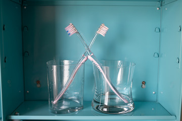 Two pink toothbrushes in dry and wet glasses on blue metal cabinet, About LGBT lifestyle, Bathroom concept