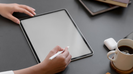 Cropped shot of a woman drawing on mock up tablet on black table background