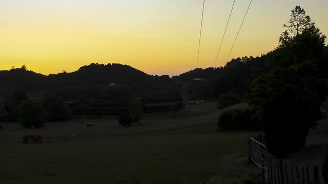 Sunset falling behind a hill in front of a field in Pataua North in New Zealand