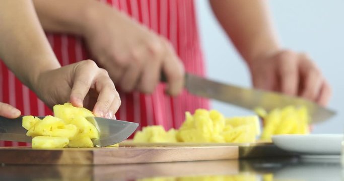 Close up scene video of two people cutting juicy pineapple by sharpening knife into small pieces.
