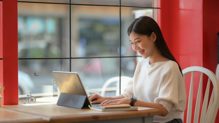 Portrait of adorable college girl working on her assignment with tablet