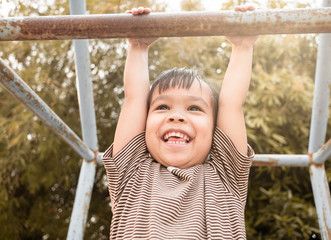 Fototapeta premium Cute Asian little girl hanging the monkey bars by her hand to exercise at out door playground on sunny day.
