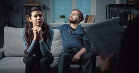 Frustrated young family having conversation with professional psychologist at therapy session. Experienced doctor helping people to solve emotional problems and find mutual understanding - Powered by Adobe