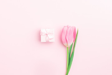 Minimal flower composition. Pink tulip and present box on pink pastel background. Flat lay, top view, copy space, mock up.