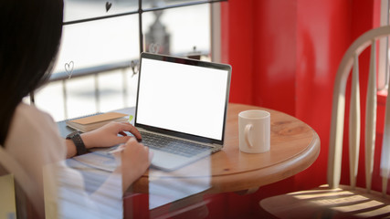 Cropped shot of a women using blank screen laptop in stylish coffee shop