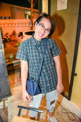 Asian woman with a perfect white smile standing near brick wall.