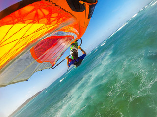 Selfie photo of flying windsurfer over Pacific ocean on the colored sail