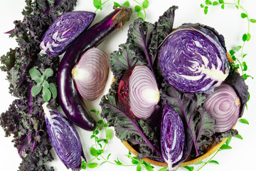 A variety of healthy raw purple vegetables on white background