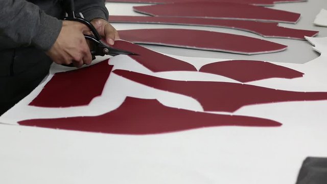 Men's hands with scissors cut bard skin glued to white backing