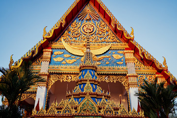 Highly decorated red-golden roof of Wat temple depicting buddha and disciples.
