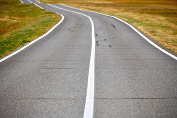 Road in a field on a summer day. Asphalt road for cars in the field.