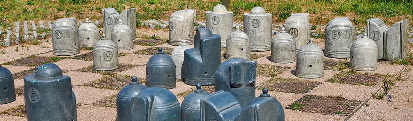 Stone chess pieces on the ground. Stylized chess Board with stone chess pieces outdoor in the park.