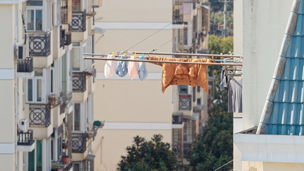 Laundry washed clothes hanging out of windows in sunny day with blur buildings background. Typical...