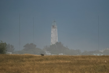 Fototapeta na wymiar Lighthouse on the cape of foggy coast, Crimea